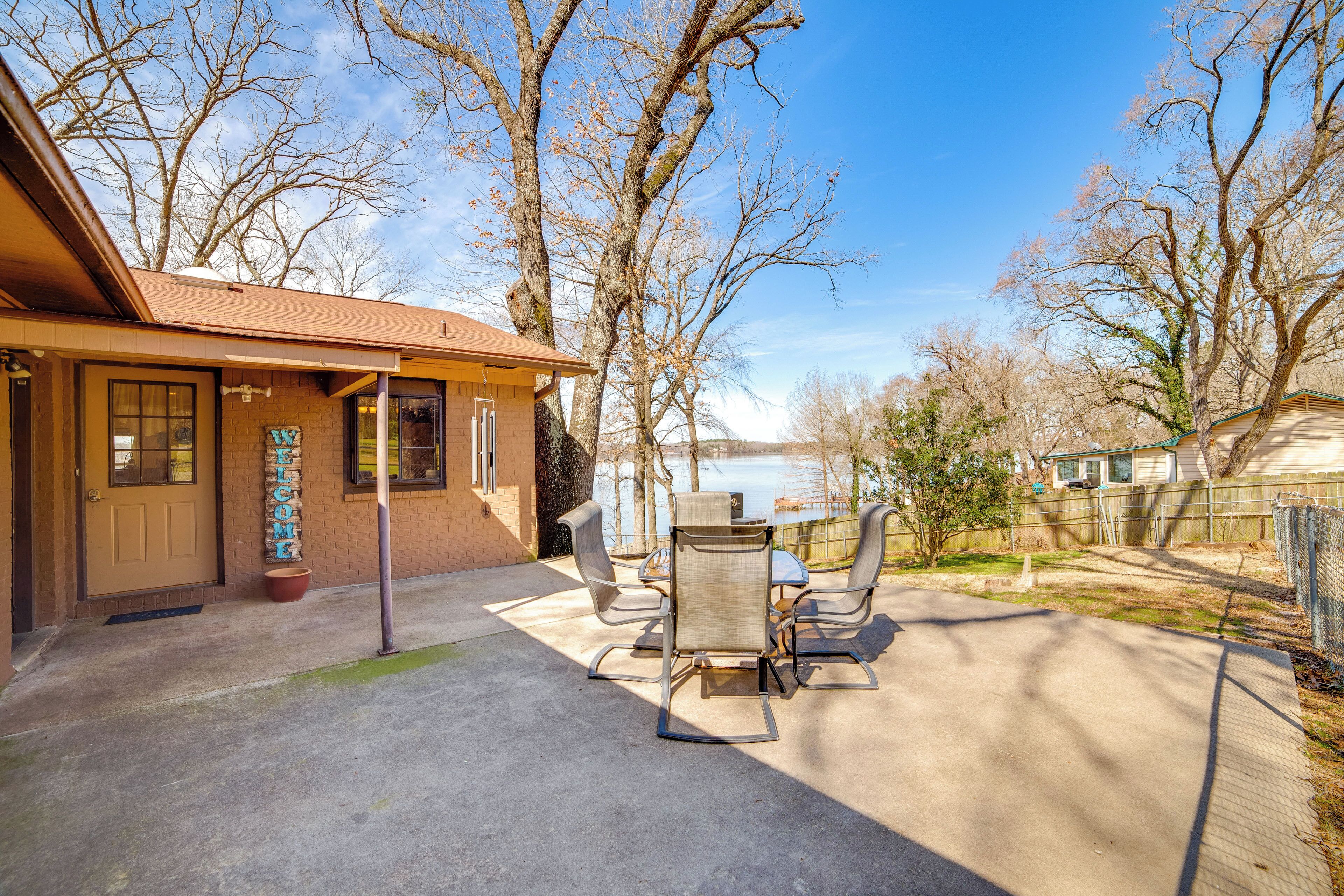 A patio with a table and chairs, a welcome sign, and a view of a lake.