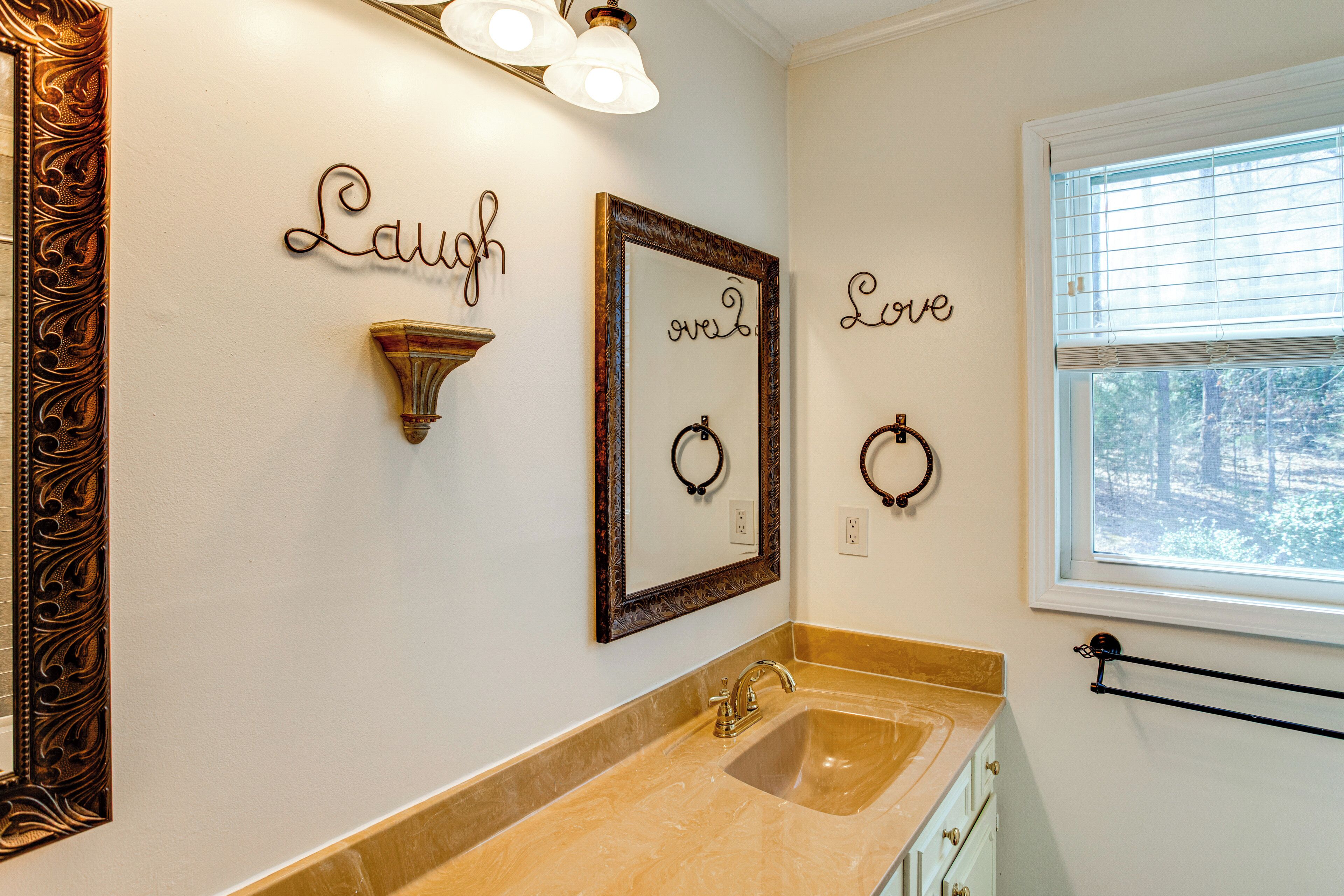 Un baño con lavabo, tocador y decoración de pared que incluye las palabras 'Laugh' y 'Love'.