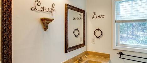 Un baño con lavabo, tocador y decoración de pared que incluye las palabras 'Laugh' y 'Love'.