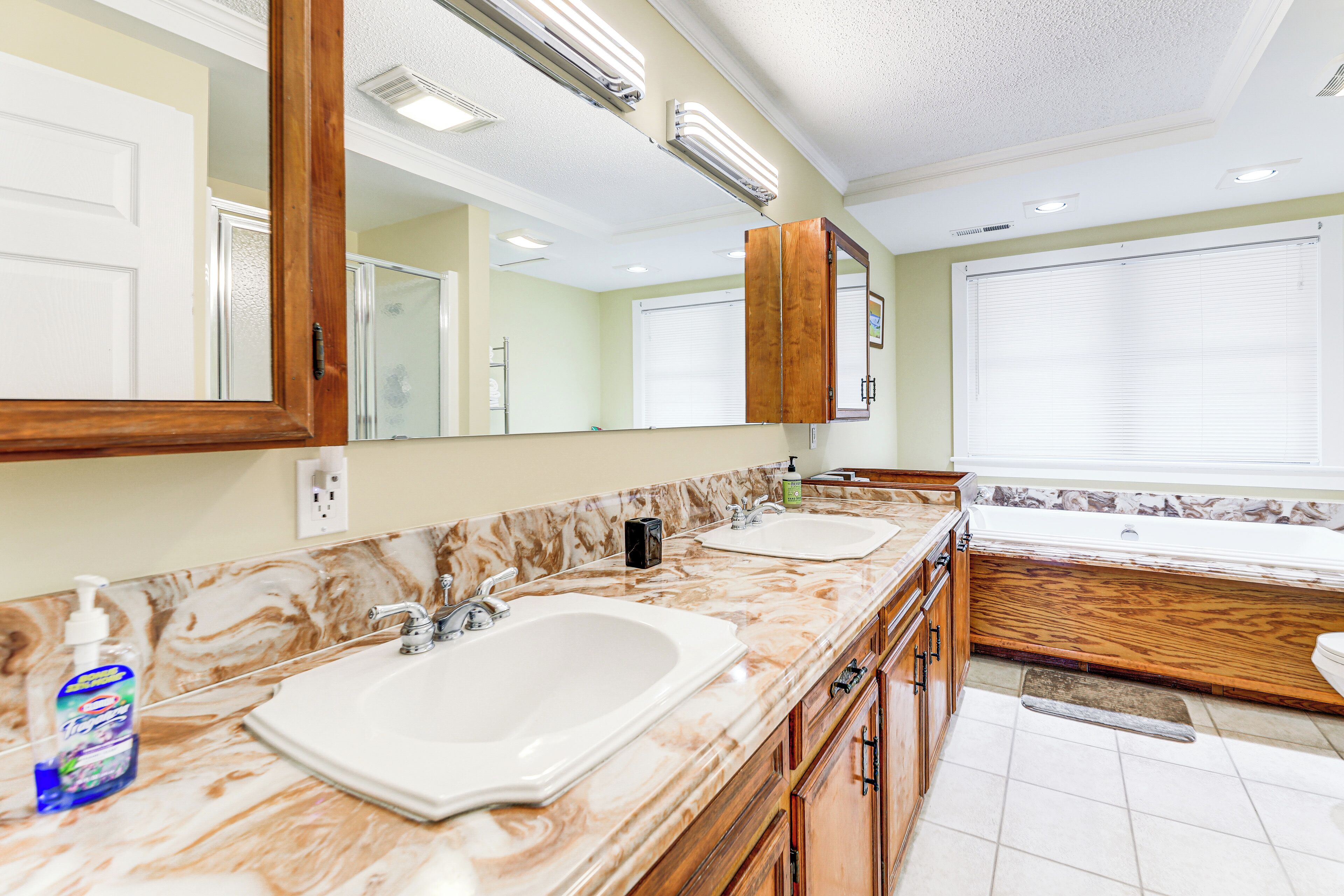 A bathroom with two sinks, a large mirror, and a bathtub.