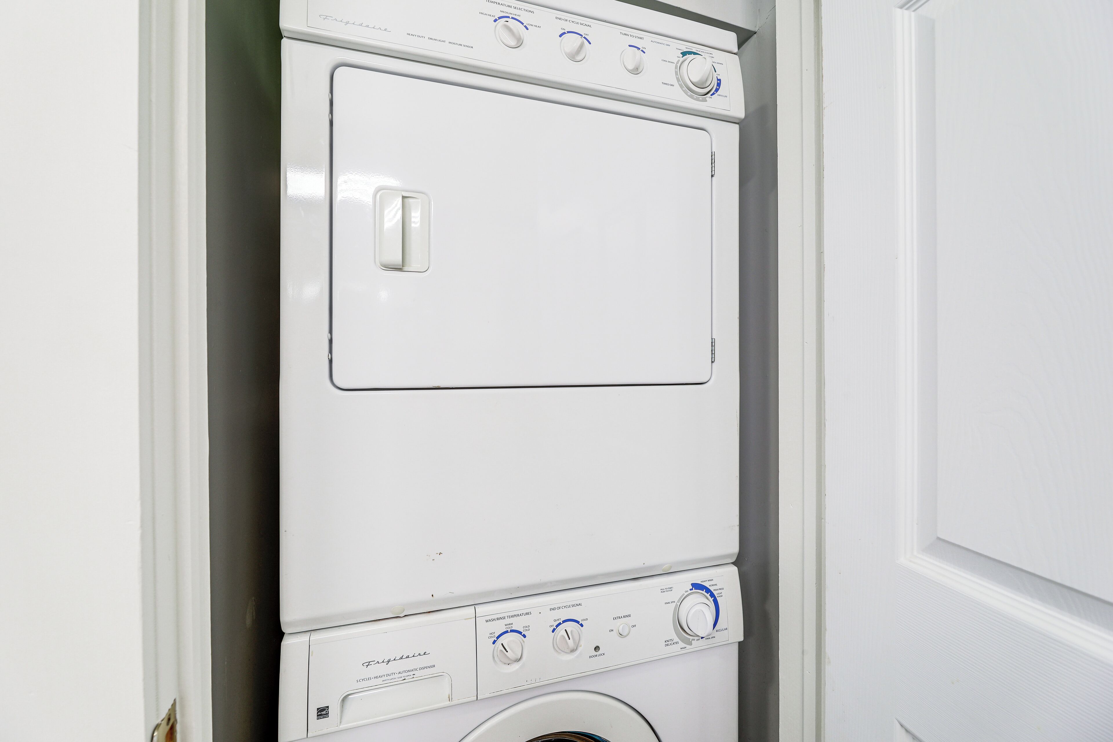 A front-loading washing machine with multiple control knobs and a front door.