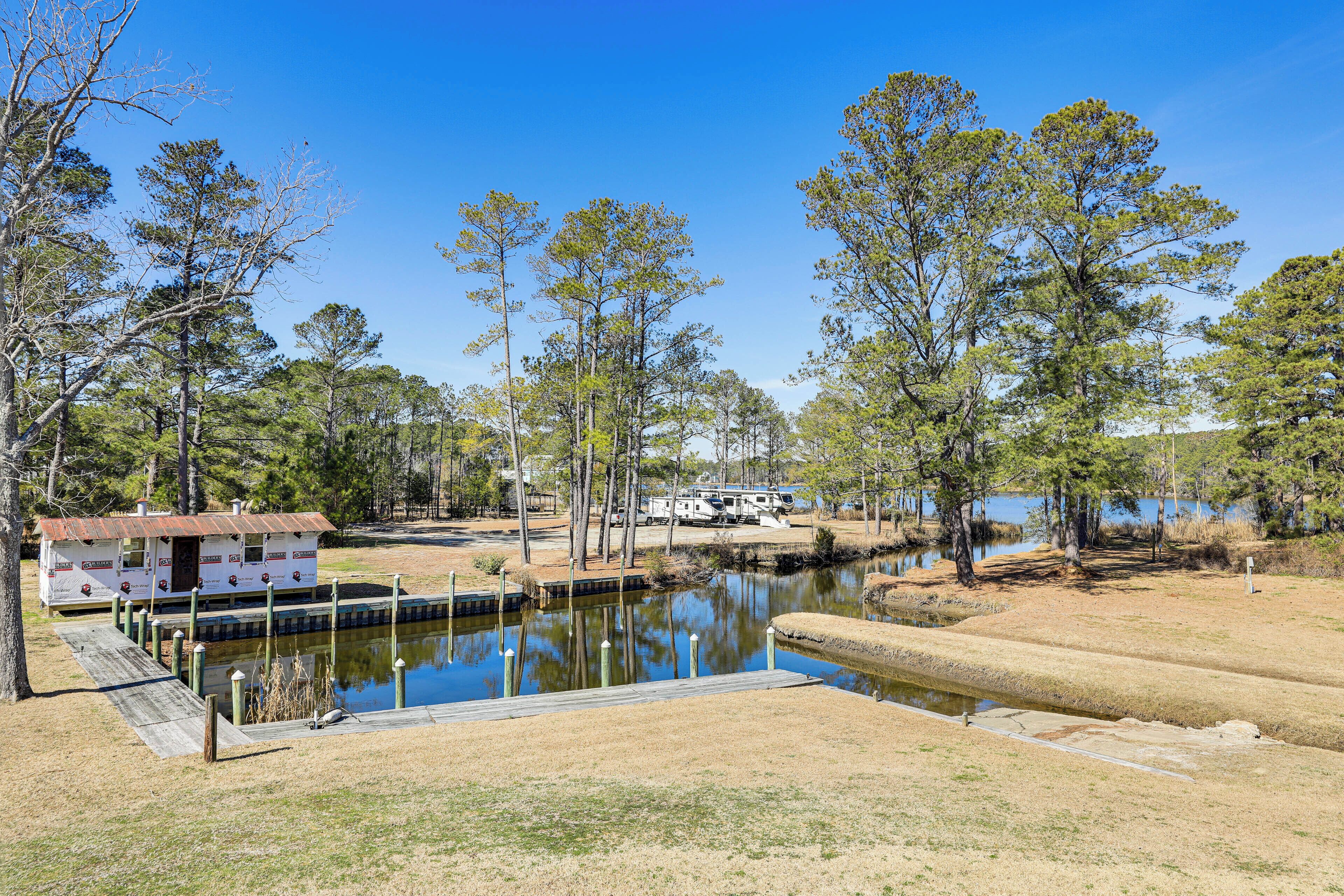 A lakeside RV park with a dock, a small cabin, and a boat.
