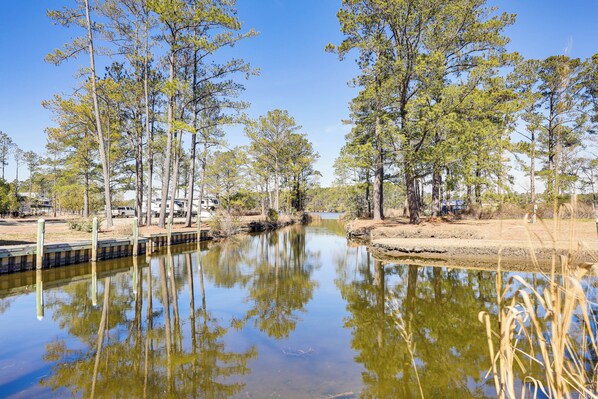 A calm water body surrounded by trees and a clear sky.