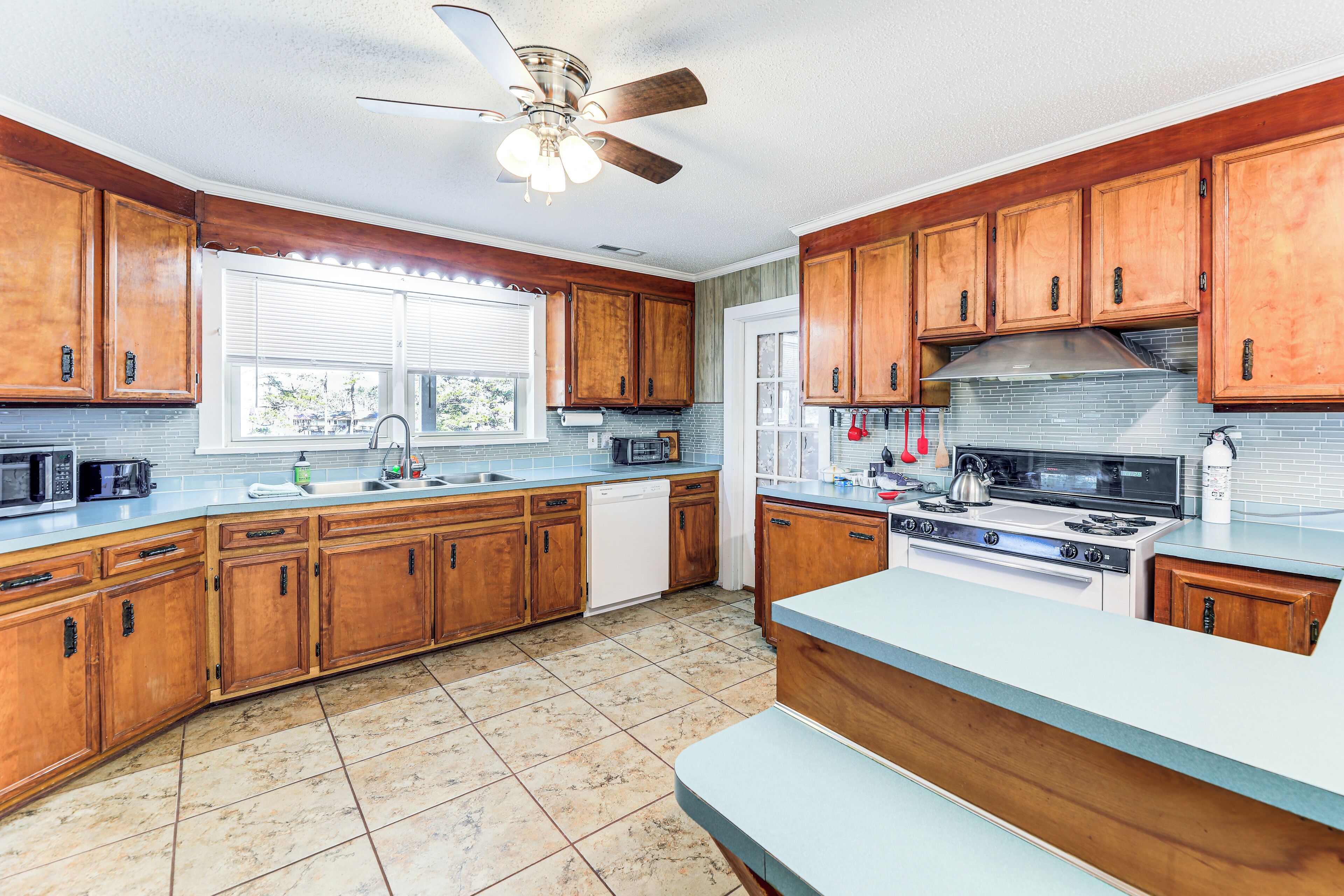 A kitchen with wooden cabinets, a stove, a microwave, and a dishwasher.