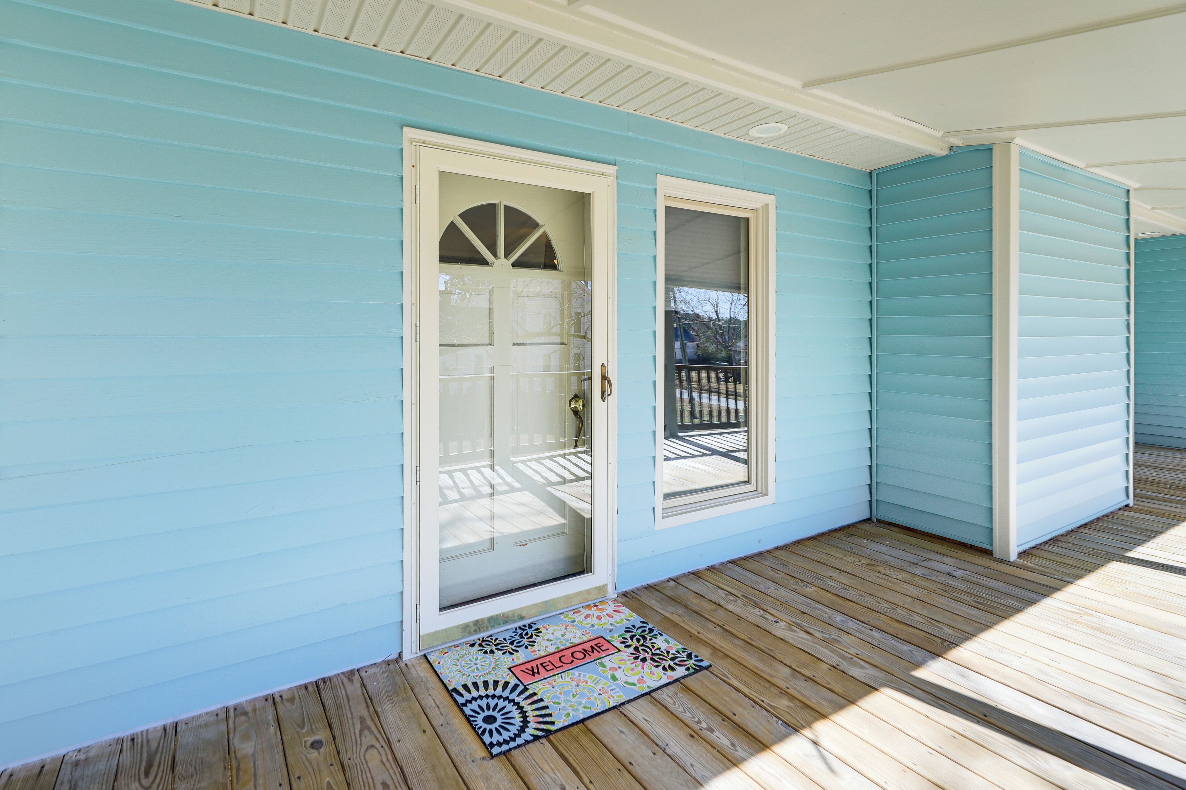 A blue house with a wooden porch and a door with a glass panel.