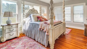 Une chambre à coucher avec un lit à baldaquin, une commode et une fenêtre équipée de stores.