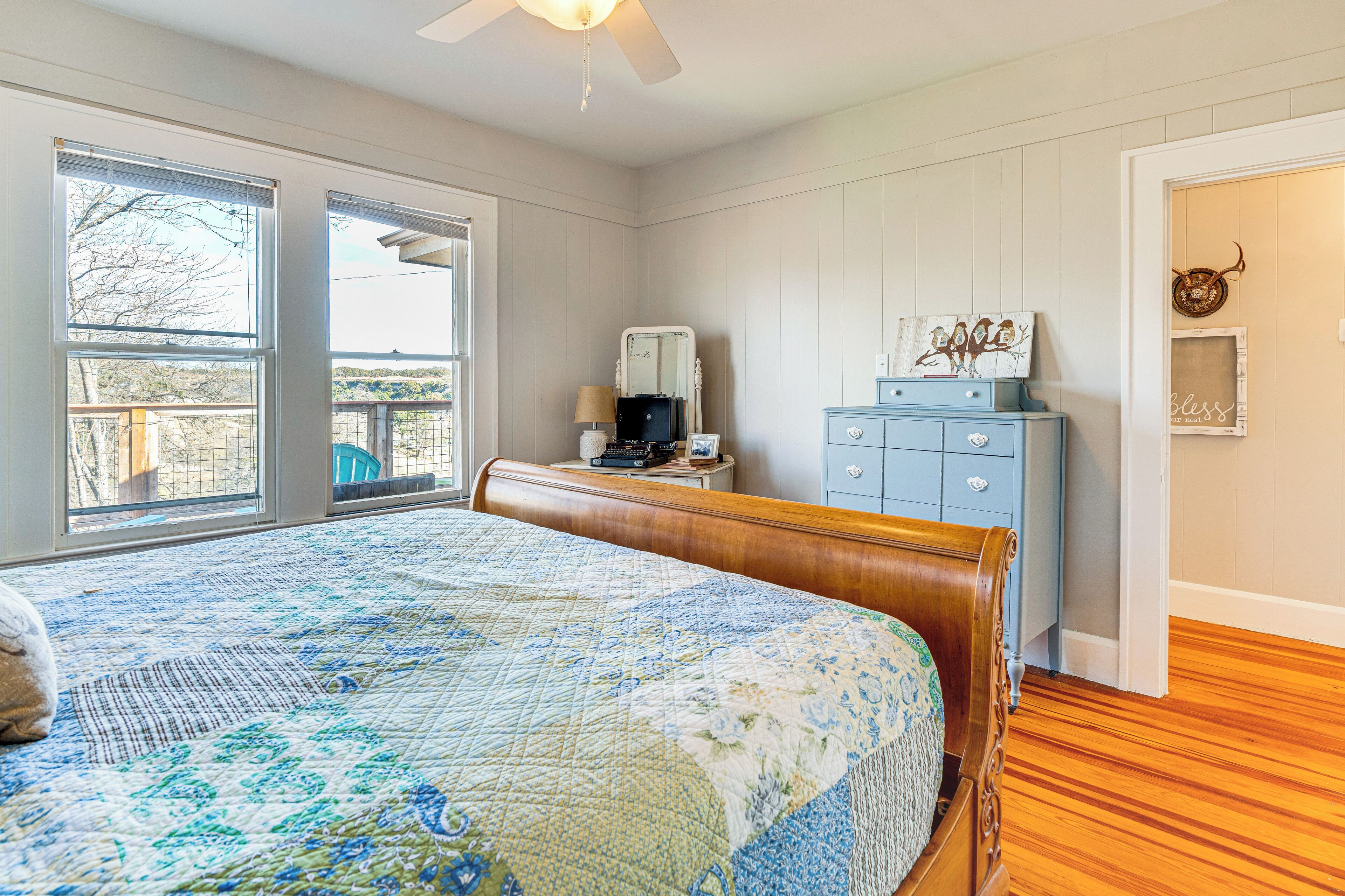 Une chambre à coucher avec un grand lit, une commode, un miroir et une fenêtre donnant sur l’extérieur.
