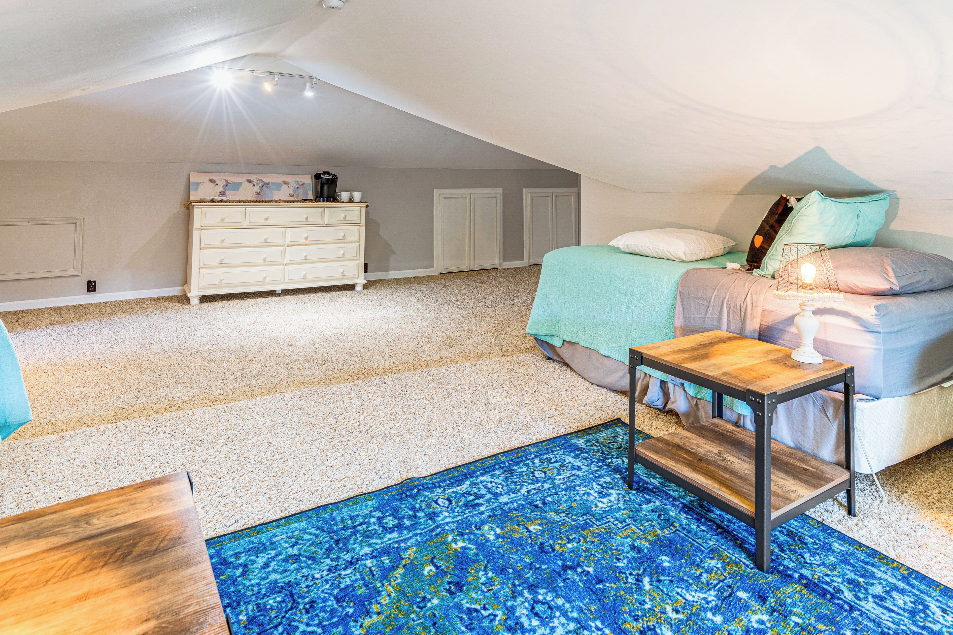 Ein Schlafzimmer mit Etagenbett, Kommode, Nachttisch und einem blauen Teppich mit Muster.