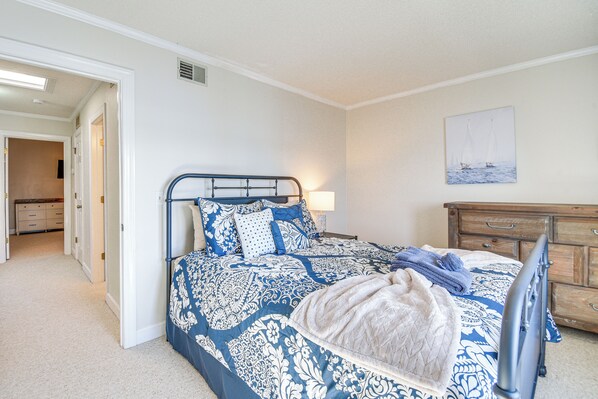 A bedroom with a bed, a dresser, a nightstand, and a painting on the wall.
