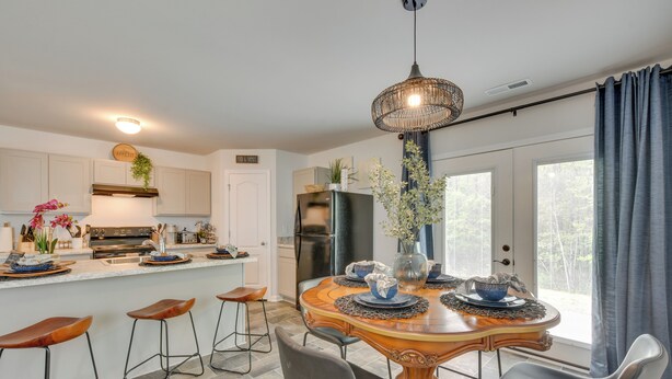Een moderne keuken met een centraal eiland, barkrukken en een eettafel voor vier personen.