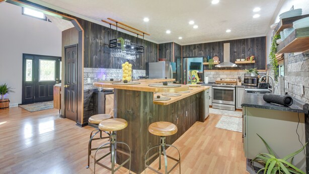 Een moderne keuken met een centraal eiland, krukken, ingebouwde apparatuur en houten details.