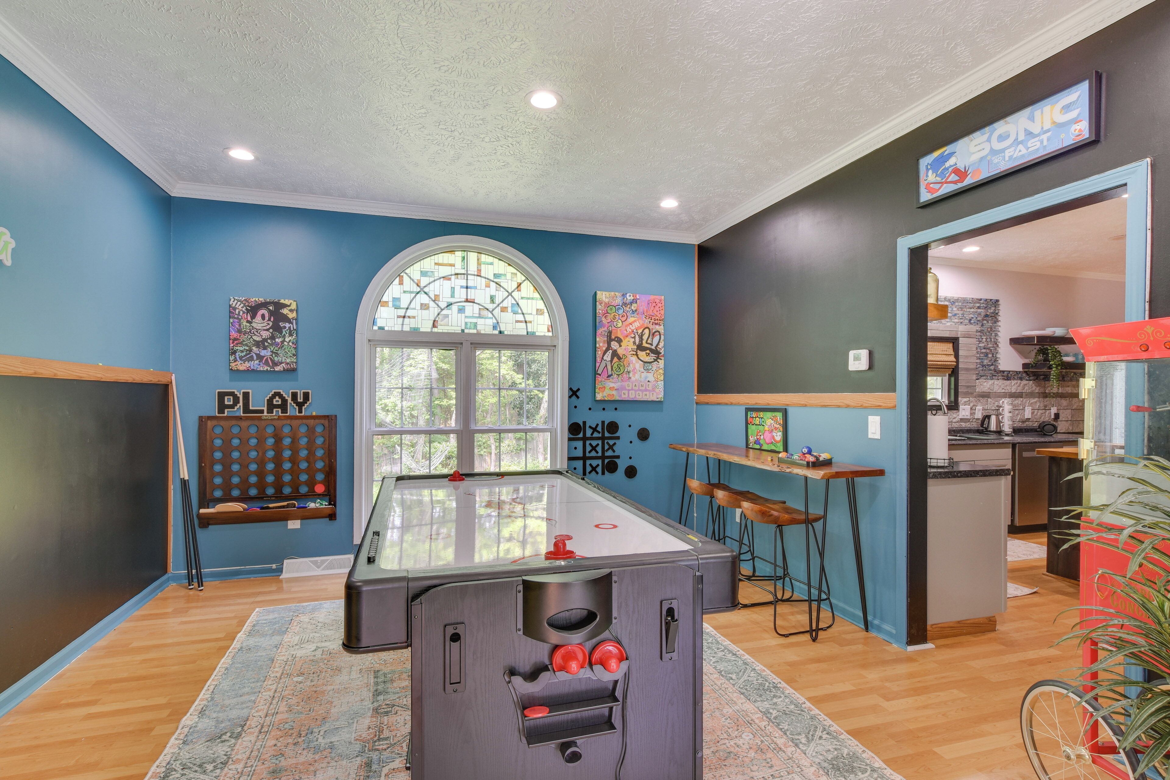 Quarto com mesa de bilhar, área de bar e cozinha visível por uma porta aberta.