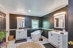 A modern bathroom with a freestanding bathtub, white cabinetry, and a large mirror above the sink. - 'peacock Landing' in Vass: Game Room & Shared Pool (Vass)