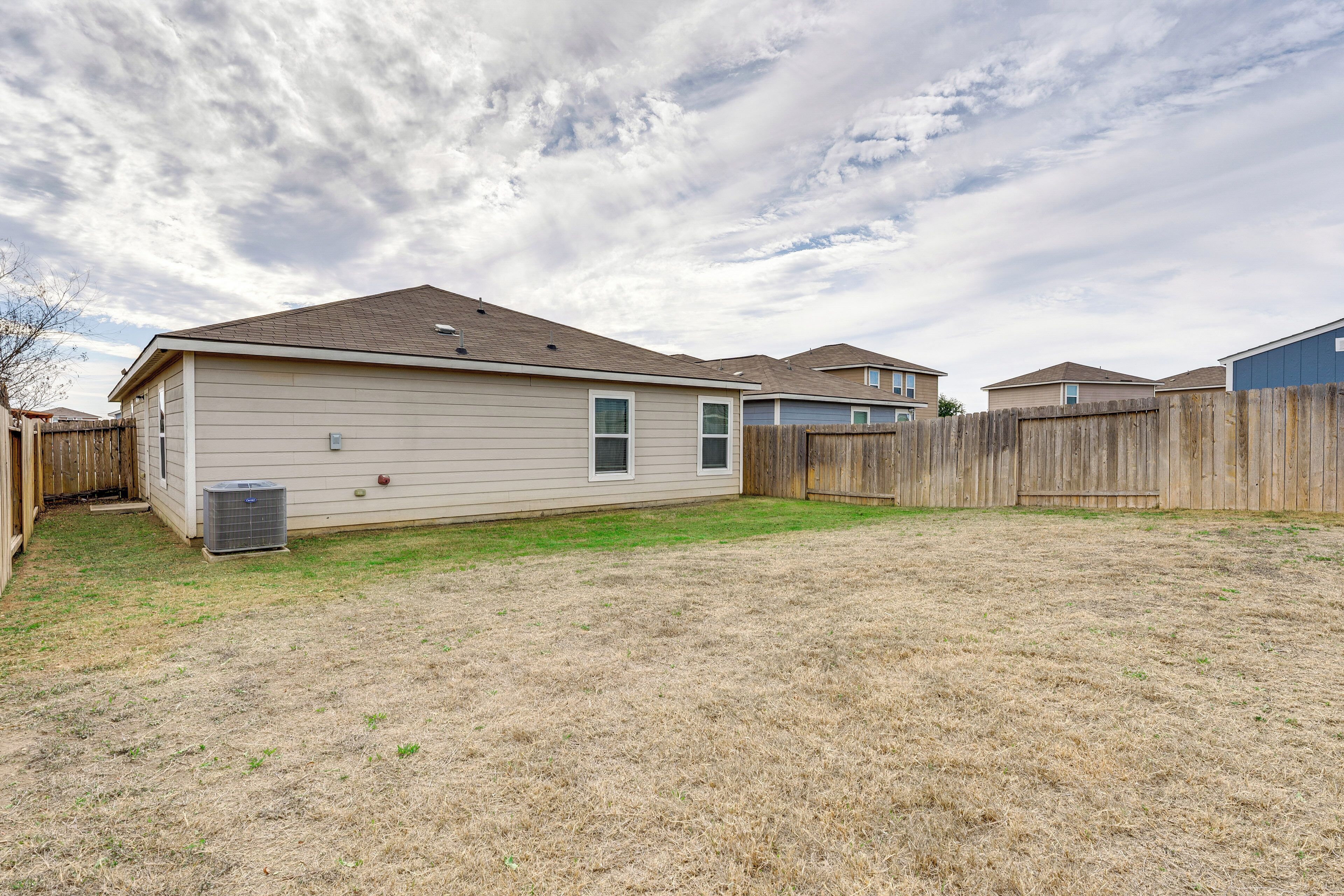 A residential backyard with a house, a wooden fence, and a lawn.