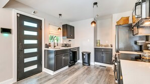 Una cocina moderna con armarios oscuros, un refrigerador de acero inoxidable y piso de madera.