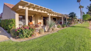 A two-story house with a covered patio, outdoor seating, and a well-maintained garden with cacti and flowering plants. - Spacious Condo w/ Mtn Views in Palm Desert! (Palm Desert)