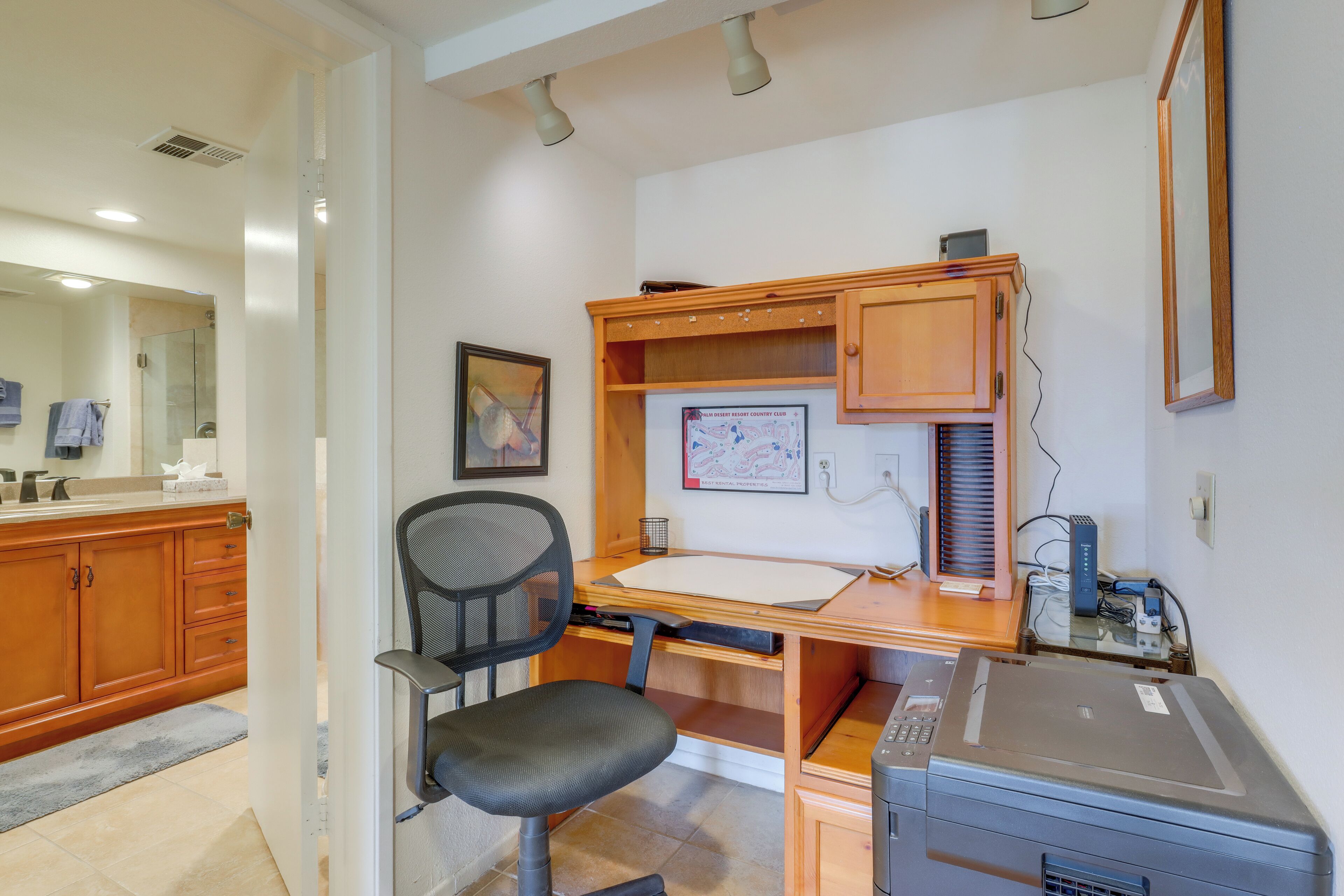 A home office with a desk, chair, printer, and a wooden cabinet.