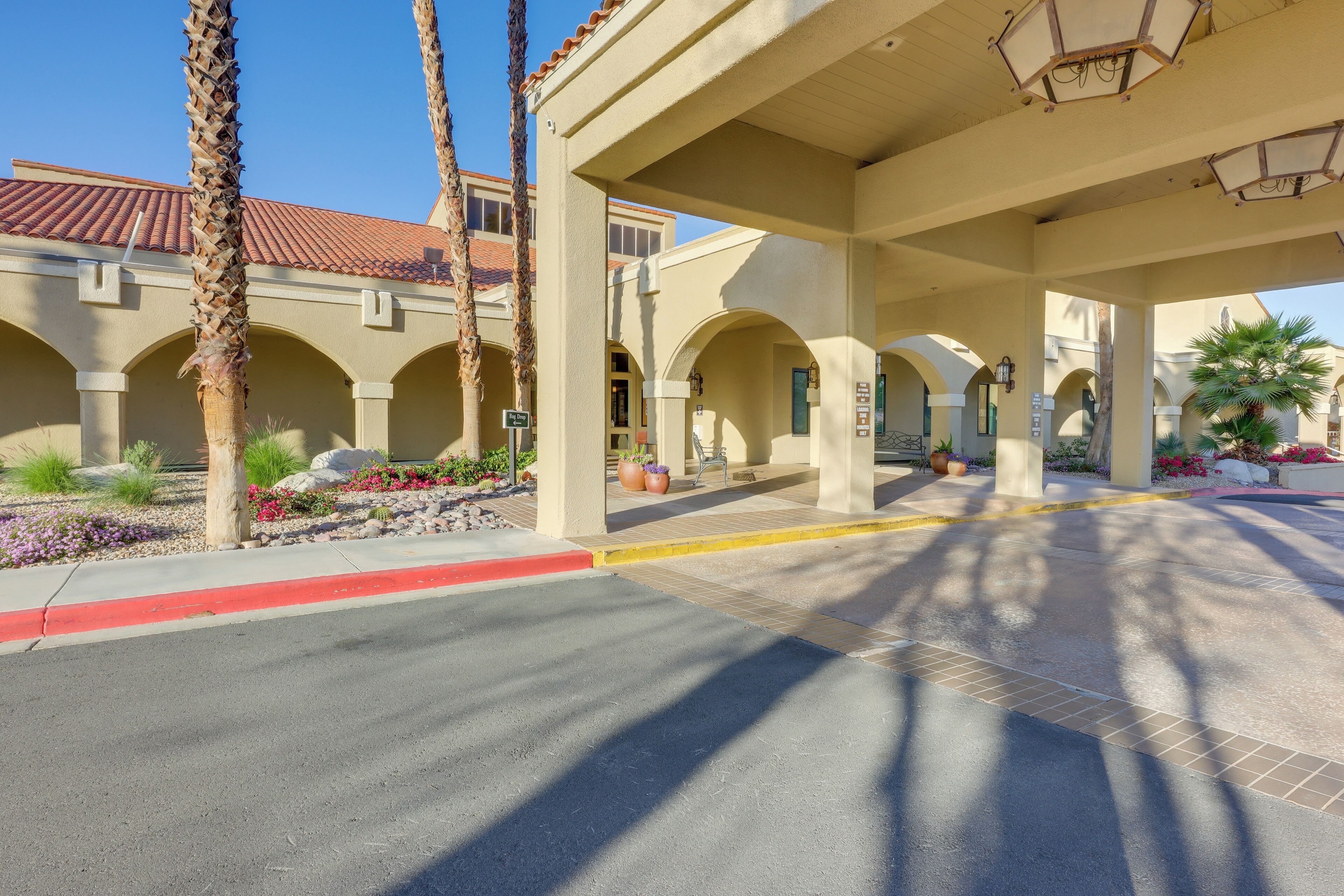 A covered outdoor area with a tiled roof, palm trees, and a red curb.