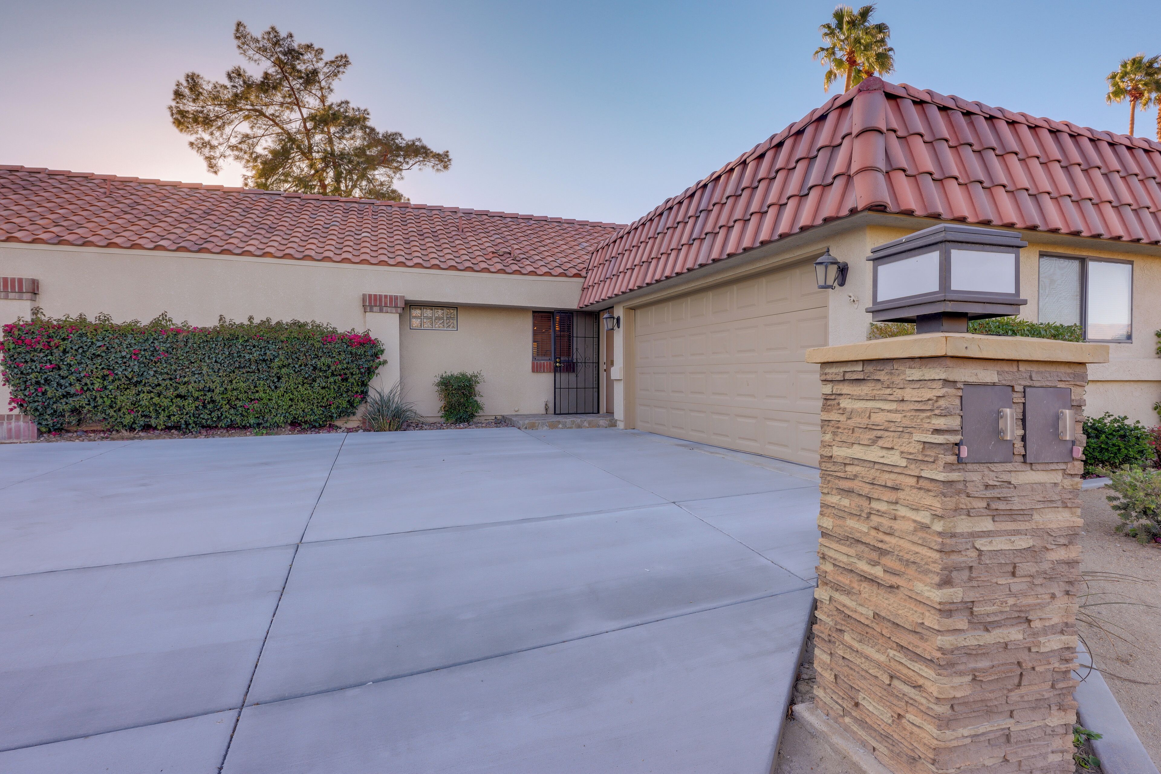 A residential house with a red-tiled roof, a stone pillar, and a garage door.