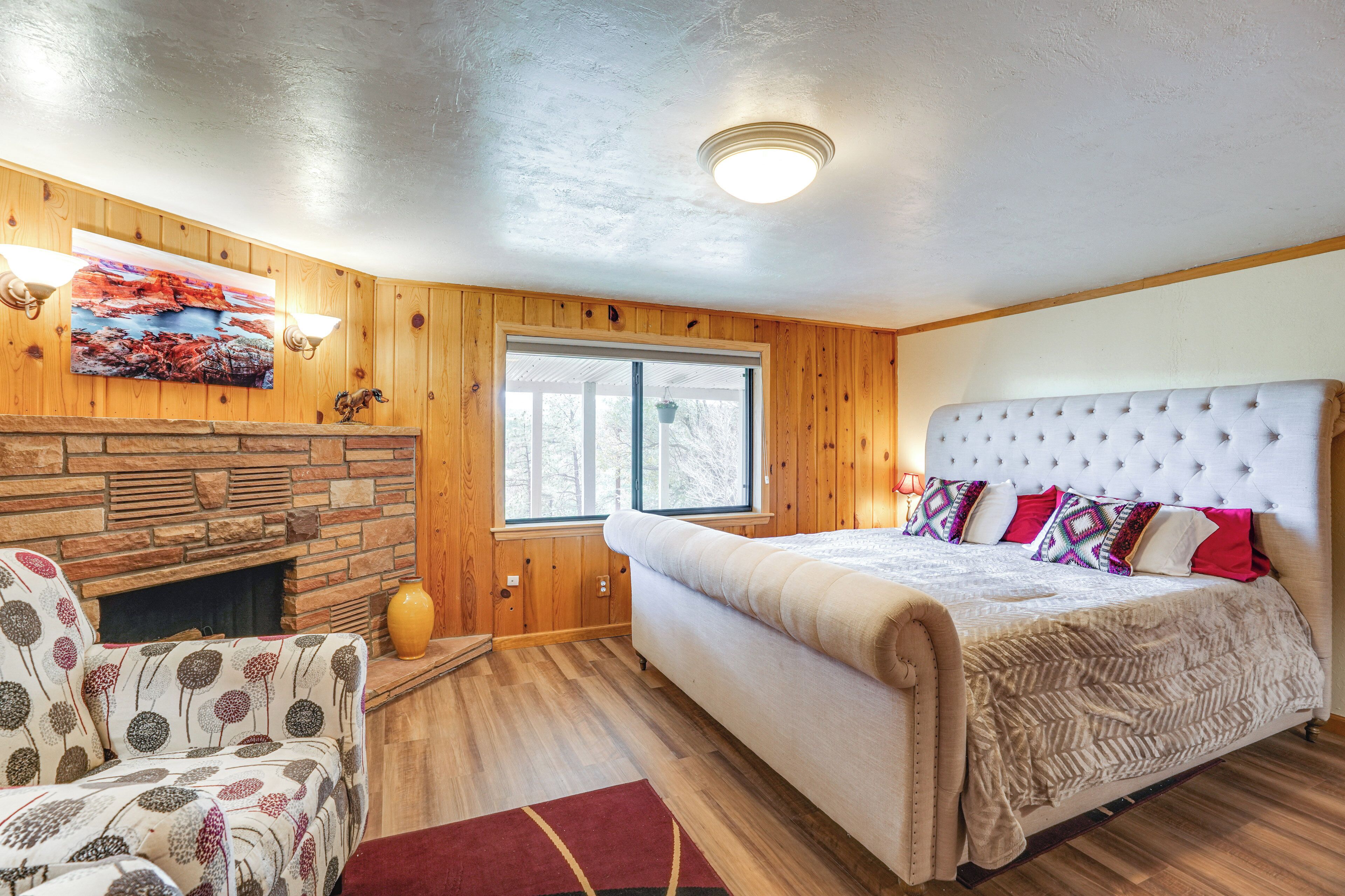 A bedroom with a large bed, a fireplace, and a window.