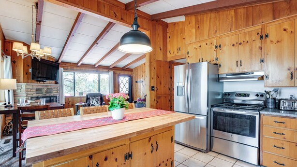 A spacious kitchen with wooden cabinets, a large island, stainless steel appliances, and a hanging light fixture. - Family Mountain Getaway, Retreat to the Cool Pine (Prescott)