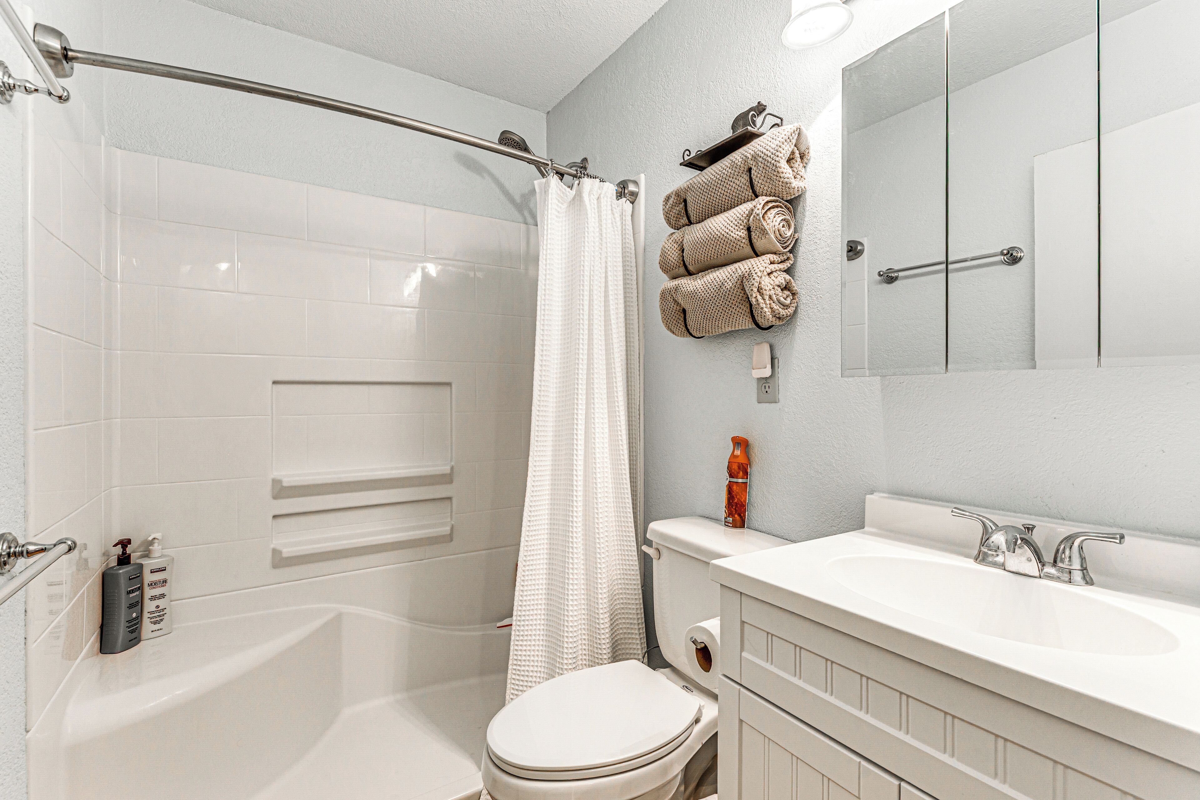 Une salle de bain avec une baignoire, des toilettes et un lavabo. On peut voir des serviettes et des articles de toilette.
