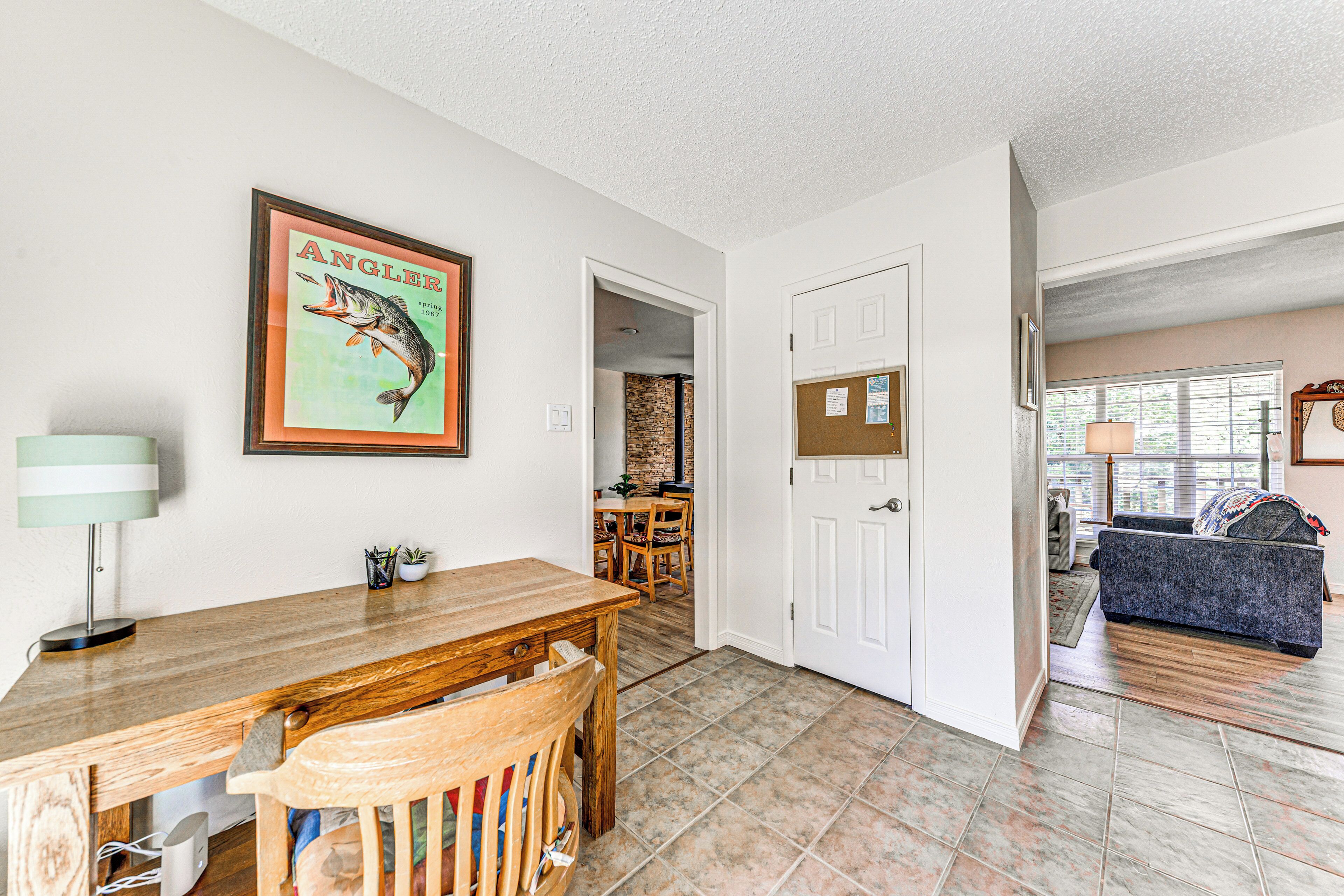 A dining area with a wooden table and chairs, a framed picture on the wall, and a door leading to another room.