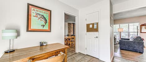 A dining area with a wooden table and chairs, a framed picture on the wall, and a door leading to another room.