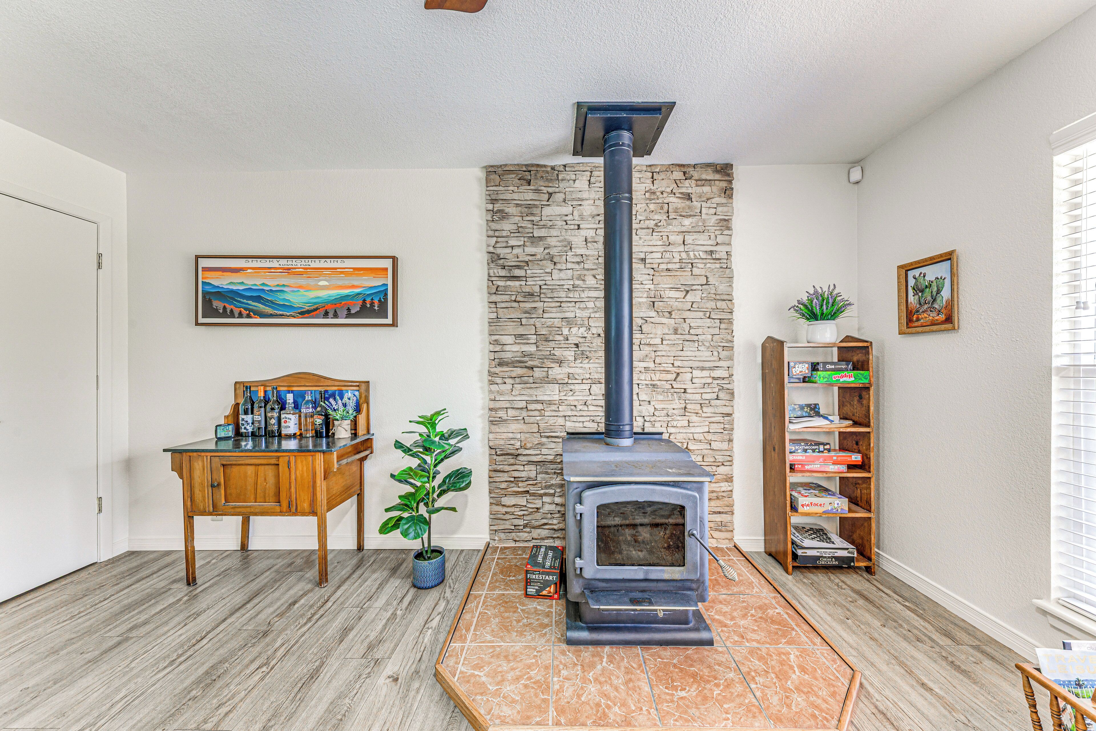 A living room with a stone wall, a fireplace, a wooden table, a bookshelf, and a door.