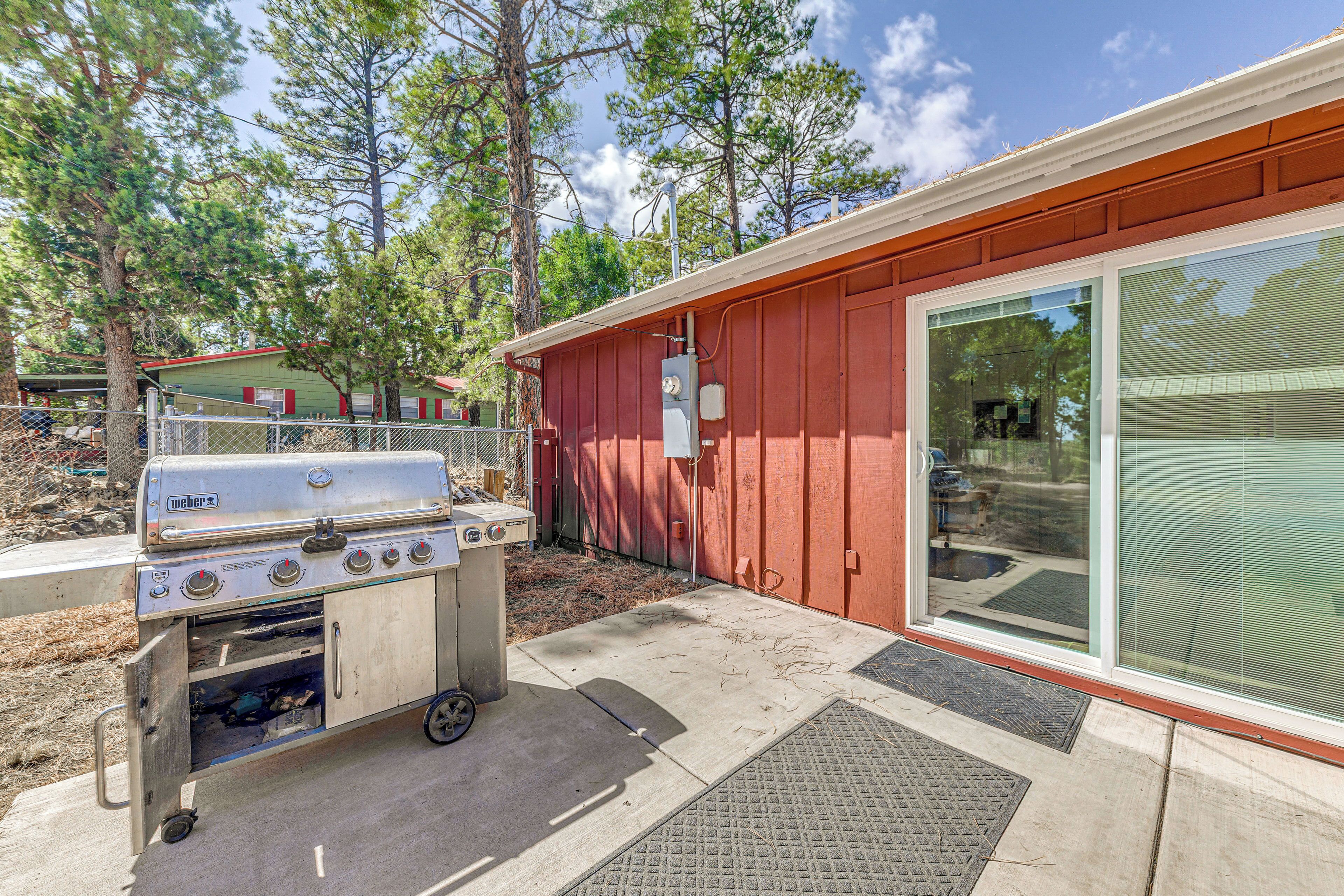 A backyard with a Weber grill, a red shed, and a large sliding glass door.