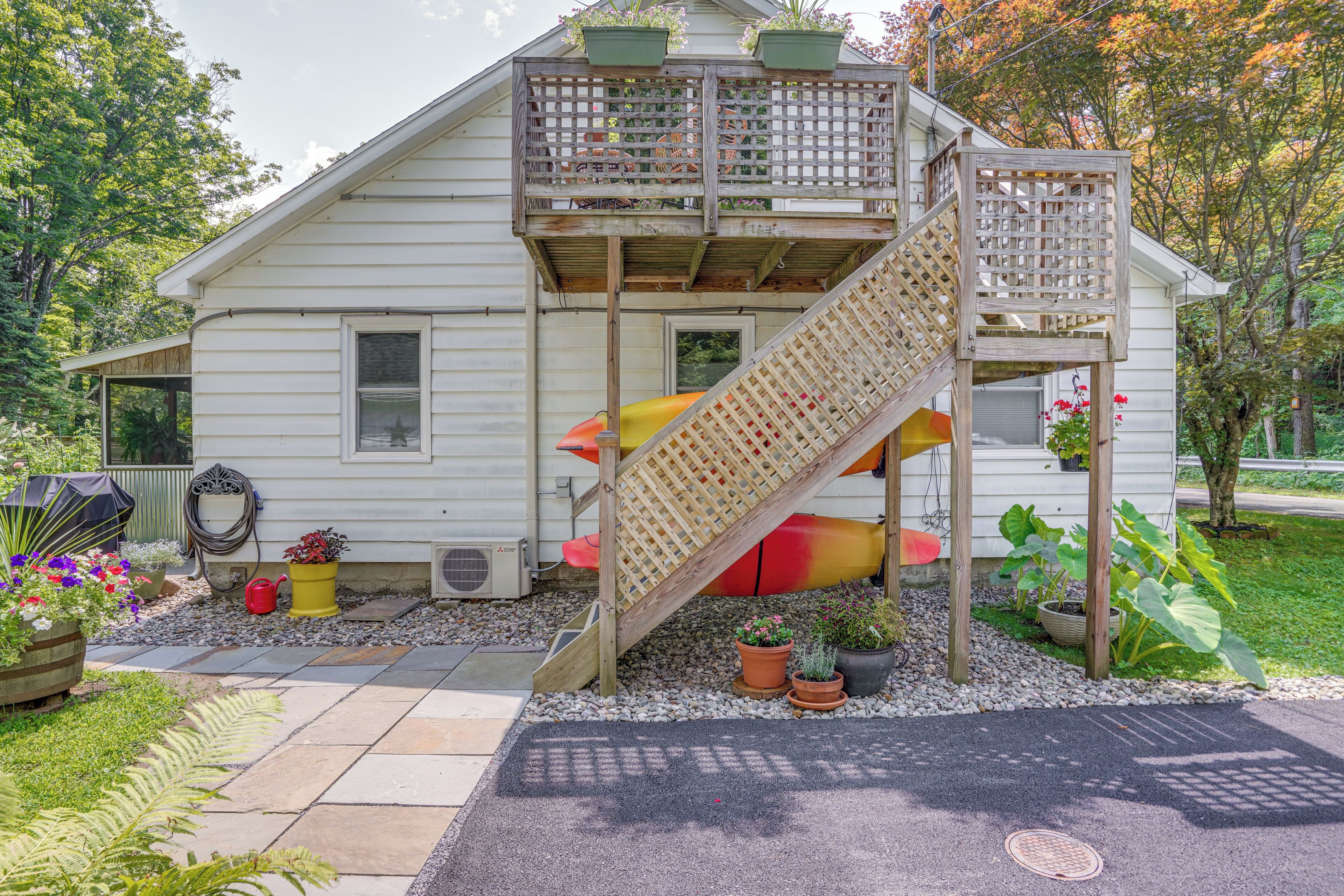 A white house with a wooden deck and a wooden staircase leading to a balcony.