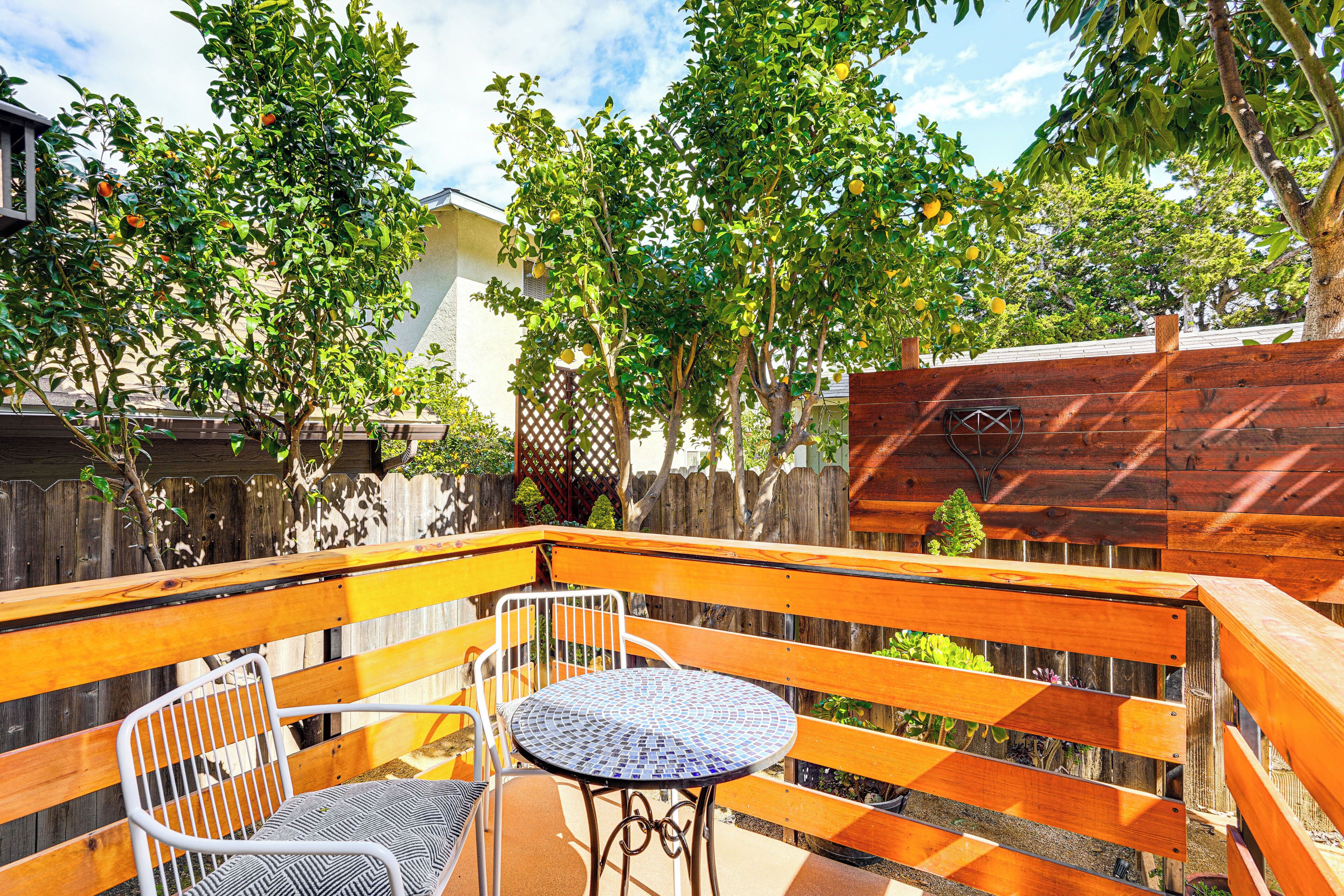 Une terrasse avec une clôture en bois, une table en métal et deux chaises.