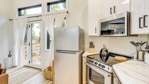 Una cucina moderna con mobili bianchi, un frigorifero in acciaio inossidabile, un piano cottura a gas e un forno a microonde.