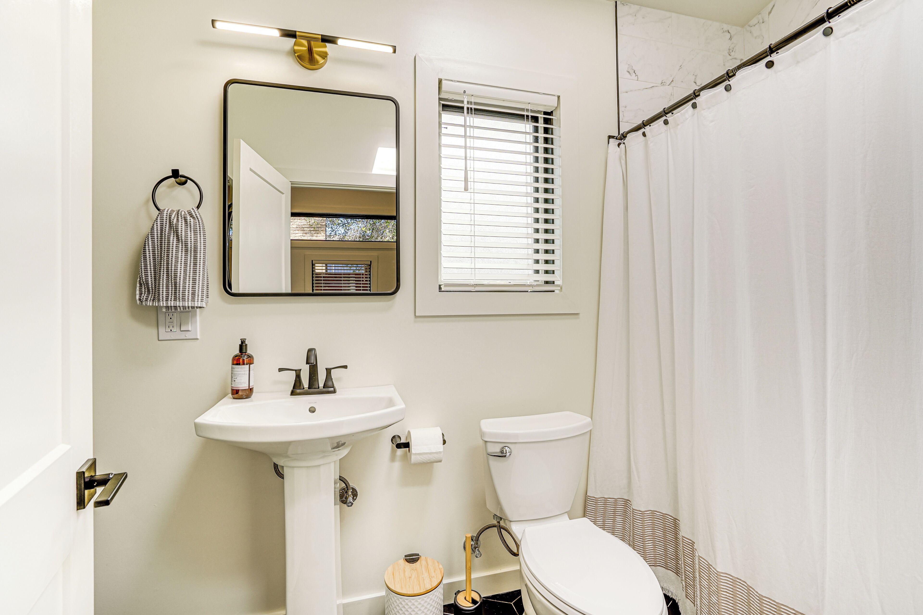 A bathroom with a white sink, mirror, toilet, and a shower curtain.