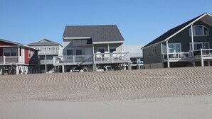 Ein strandnahes Anwesen mit mehreren Häusern, darunter ein auffälliges Haus mit Balkon und ein kleineres Haus mit Veranda.
