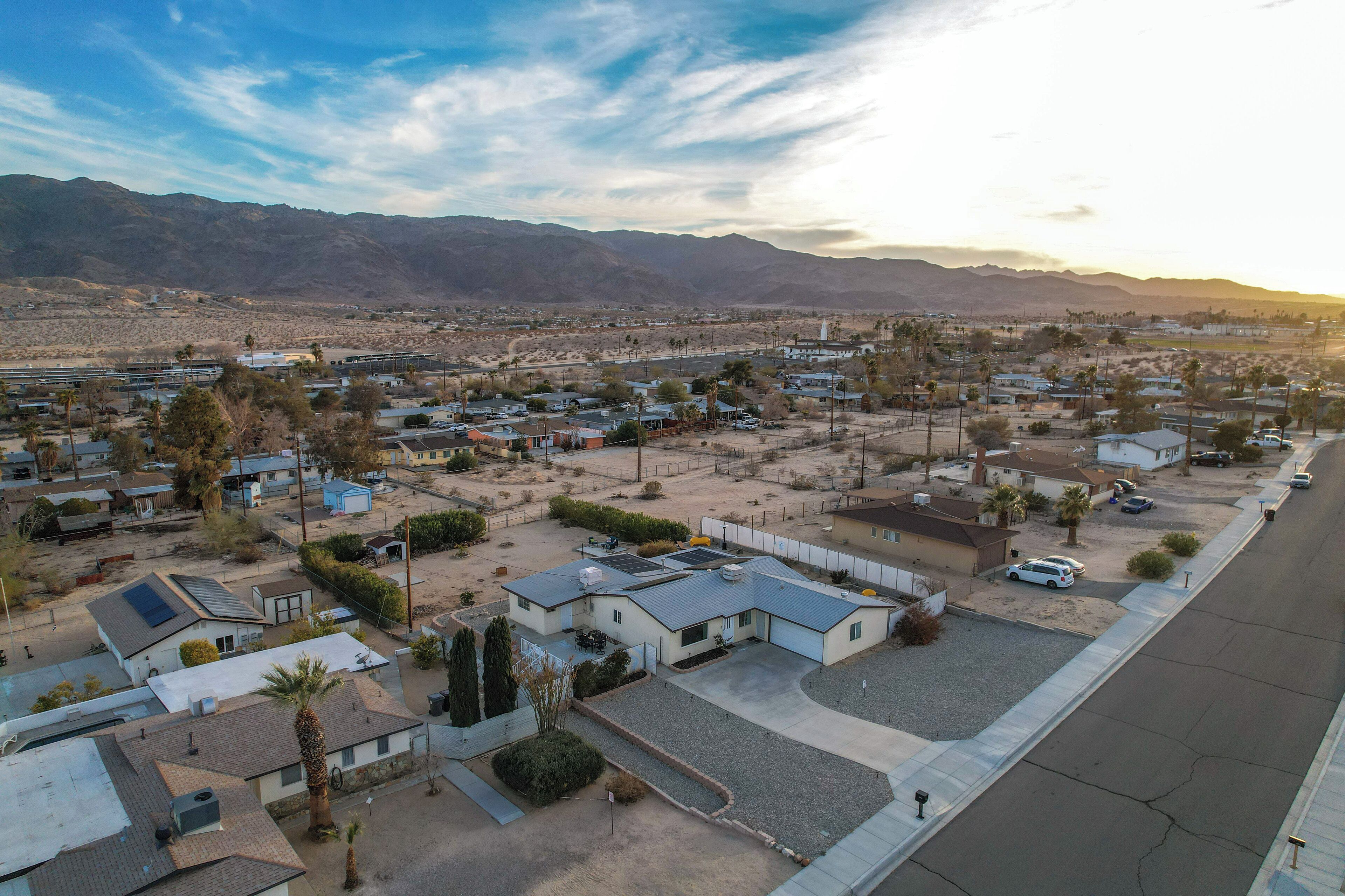A residential area with houses, a street, and mountains in the background.