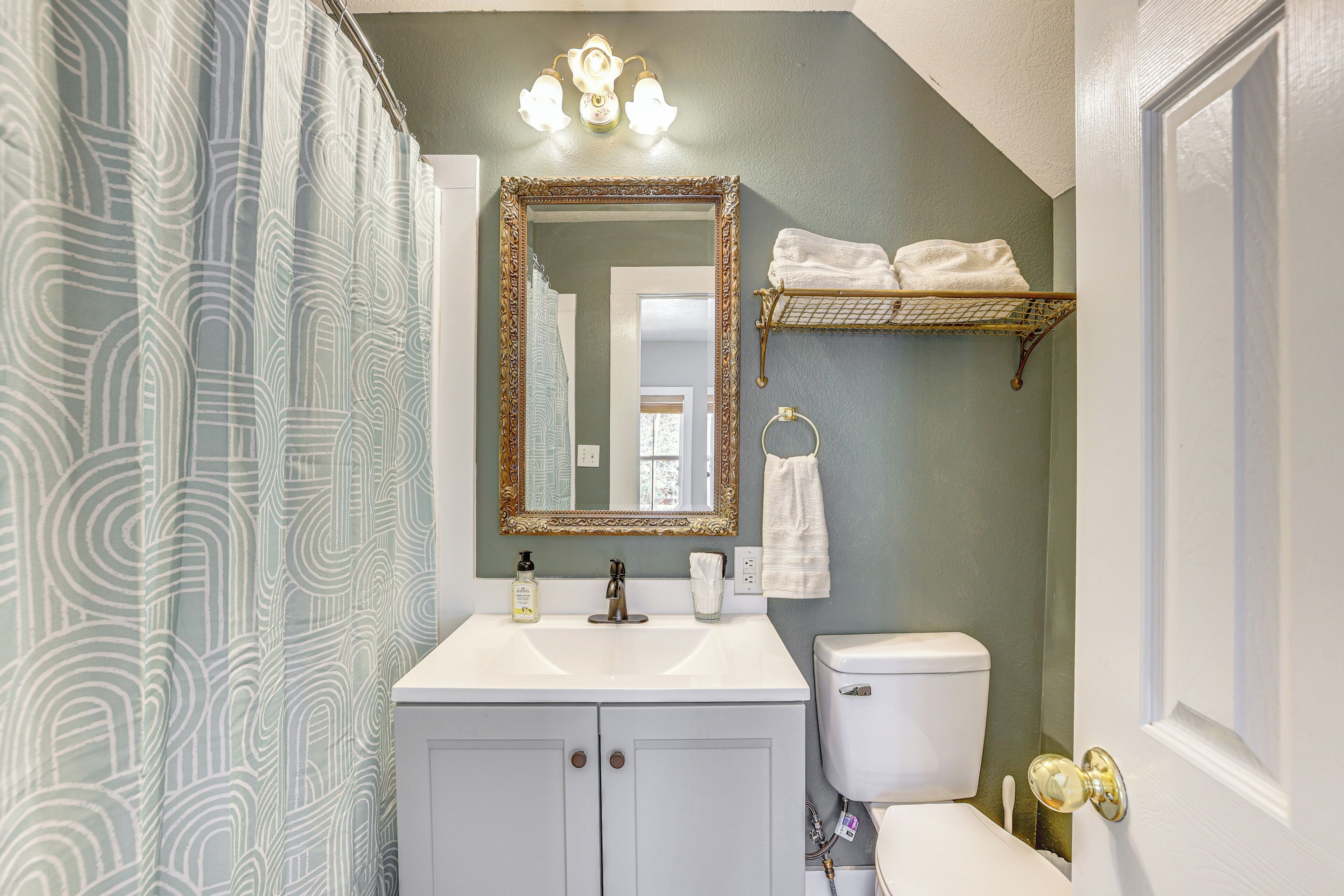 A bathroom with a white vanity, a large mirror, a towel rack, and a toilet.