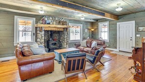 A cozy living room with a stone fireplace, leather furniture, and wooden floors. - Historic 'mcbride House' in Garden Valley Mtns! (Garden Valley)