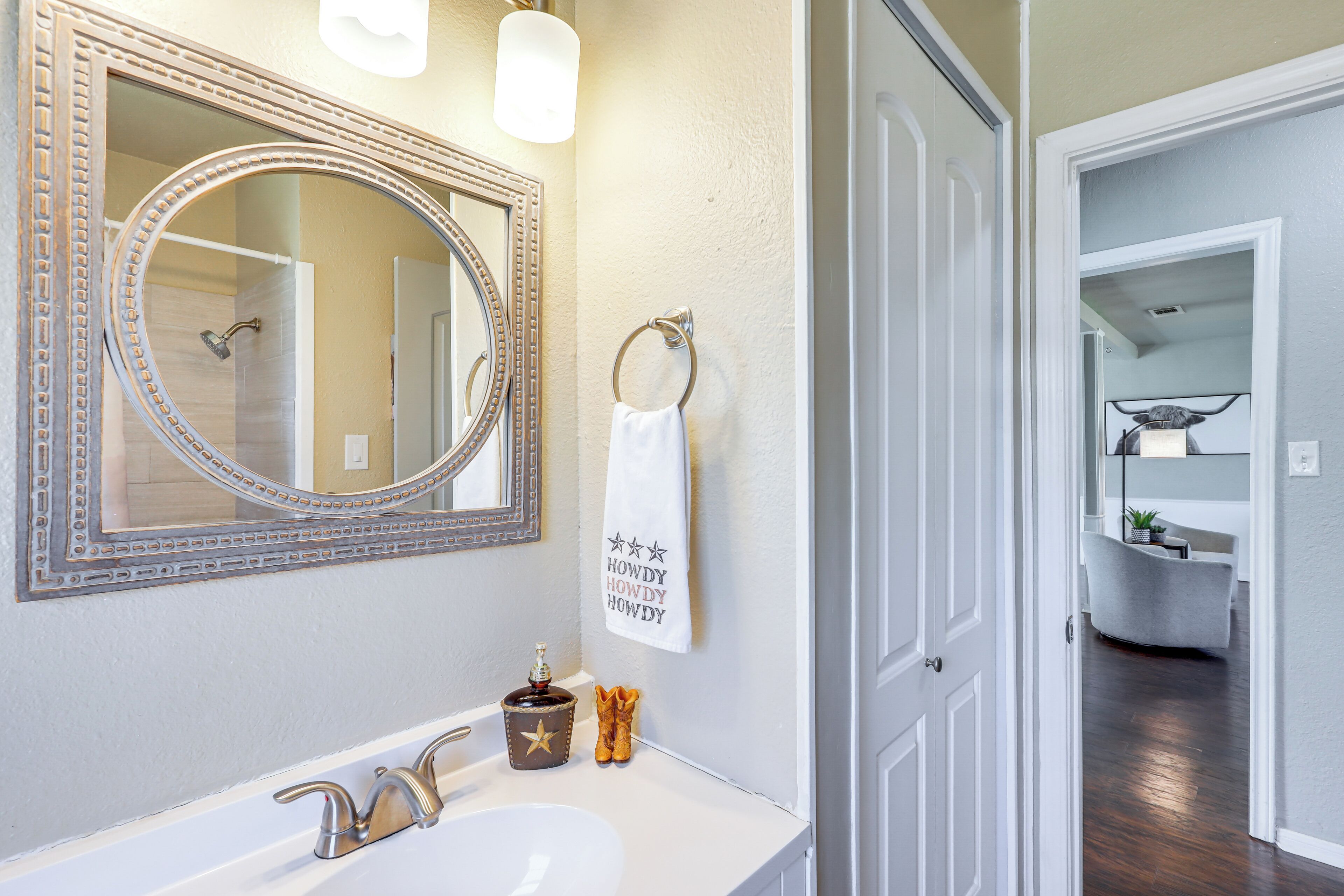 A bathroom with a large mirror, a sink, and a towel rack.