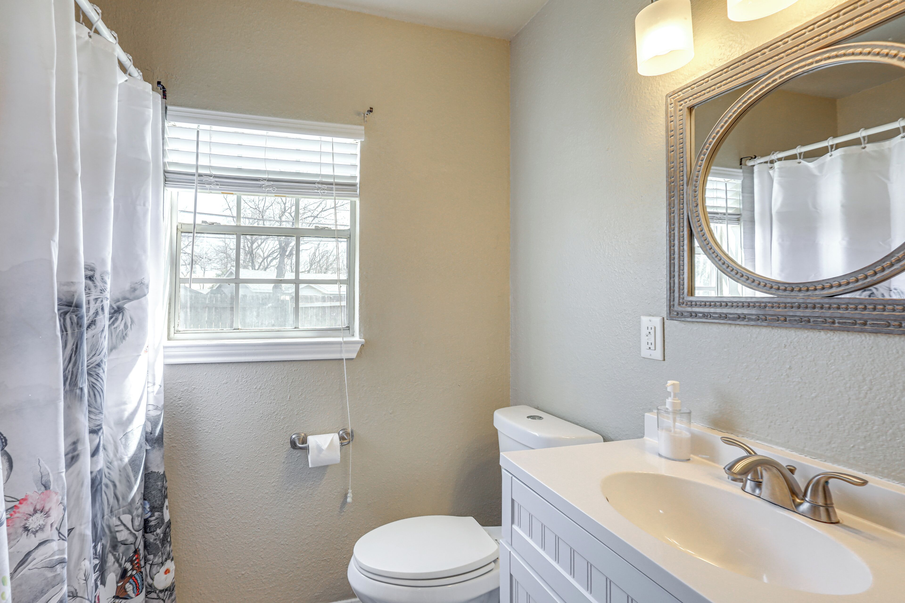 A bathroom with a toilet, sink, and shower curtain.