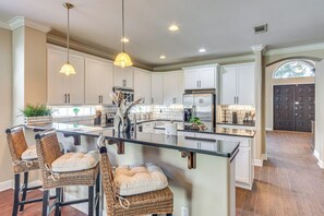 A spacious kitchen with a central island, white cabinetry, and a dark door in the background. - 8 Mi to Beach: Home in Mary Esther (Mary Esther)