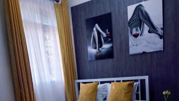 A bedroom with a bed, a nightstand, and two paintings on the wall. - Standard Gardens Milimani Kisumu (Kisumu)