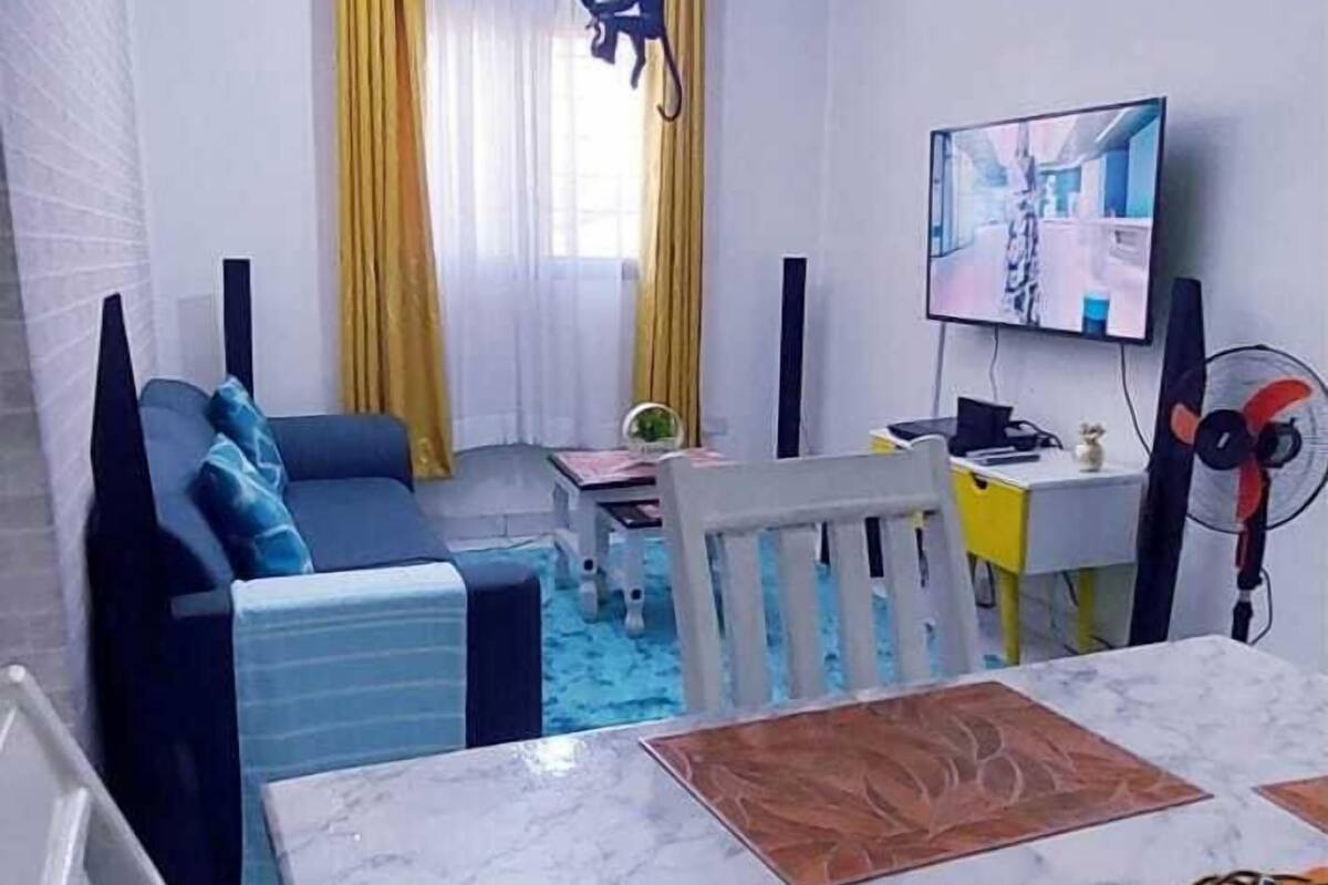 Ein modernes Wohnzimmer mit Essbereich, ausgestattet mit einer Couch, einem Couchtisch, einem Fernseher und einem Ventilator.
