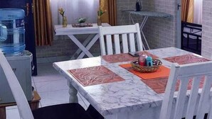 A dining area with a white table and chairs, a water dispenser, and a brick wall. - Standard Gardens Milimani Kisumu (Kisumu)