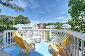 A deck with two yellow chairs, a small table, and an American flag.