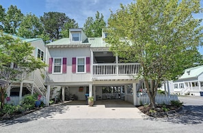 A two-story building with a balcony, a covered porch, and a small garden area.
