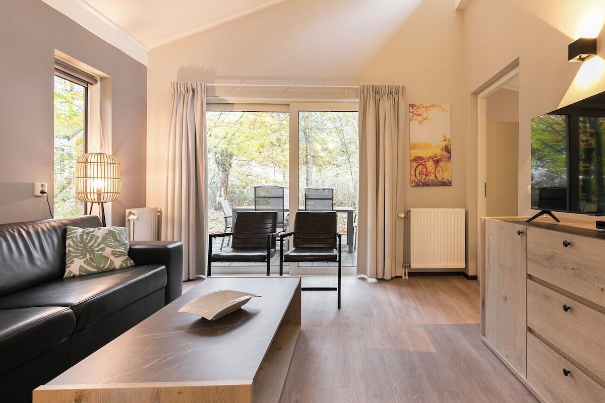 Un salon moderne comprenant un canapé, une table basse, un téléviseur et un coin repas avec des chaises et une table.