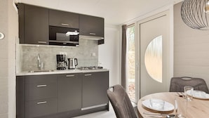 A modern kitchen with dark cabinets, a built-in microwave, a coffee maker, and a gas stove. - Summio Parc De Berkenhorst (Kootwijk)