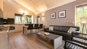A modern living room with a sofa, coffee table, and dining area. - Summio Parc De Berkenhorst (Kootwijk)