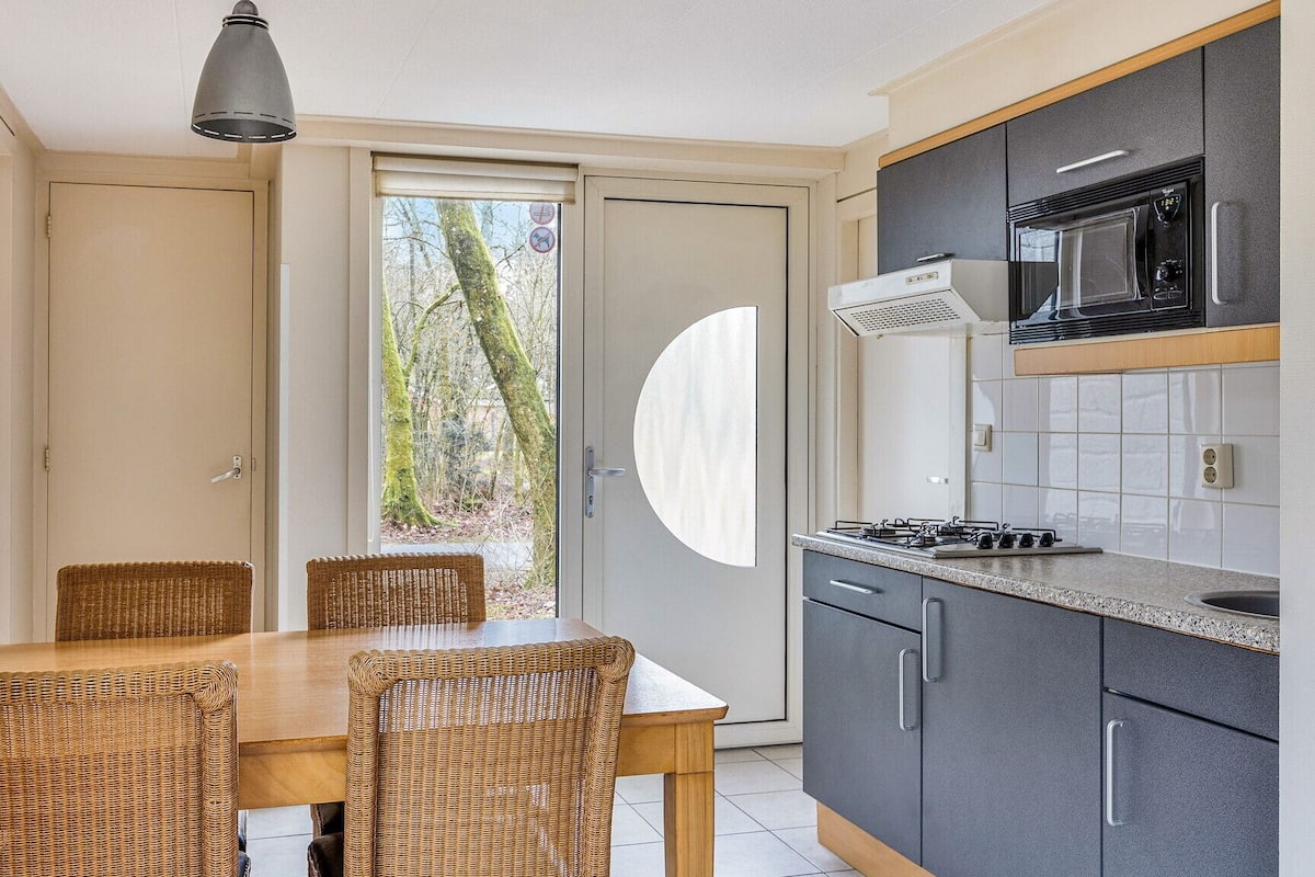 Une cuisine moderne avec un coin repas, dotée d’une grande fenêtre, d’un four à micro-ondes et d’une cuisinière à gaz.